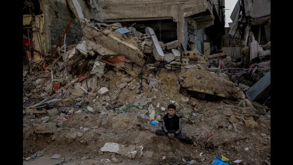 A boy sits in front of a building destroyed by a missile strike. Shujaia, Gaza City, 21 February  2024. Credit: Christian Aid/Omar Al-Qattaa