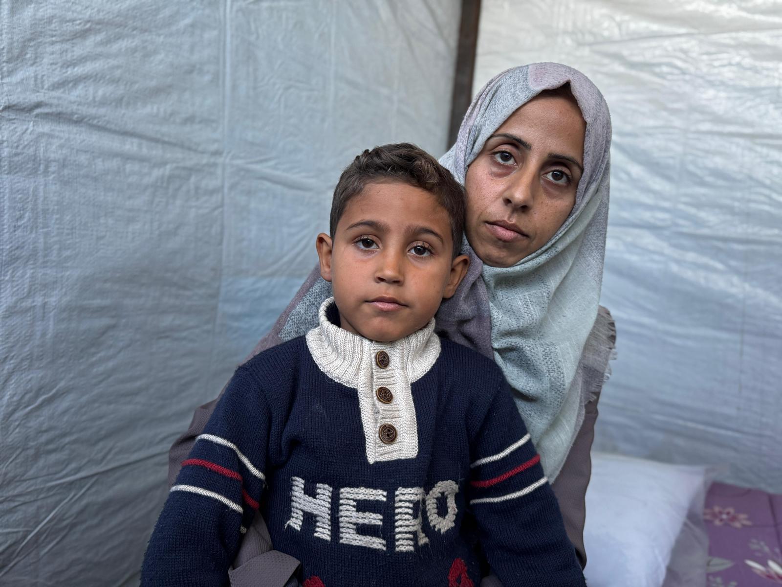 Gaza woman holding her son while looking at the camera