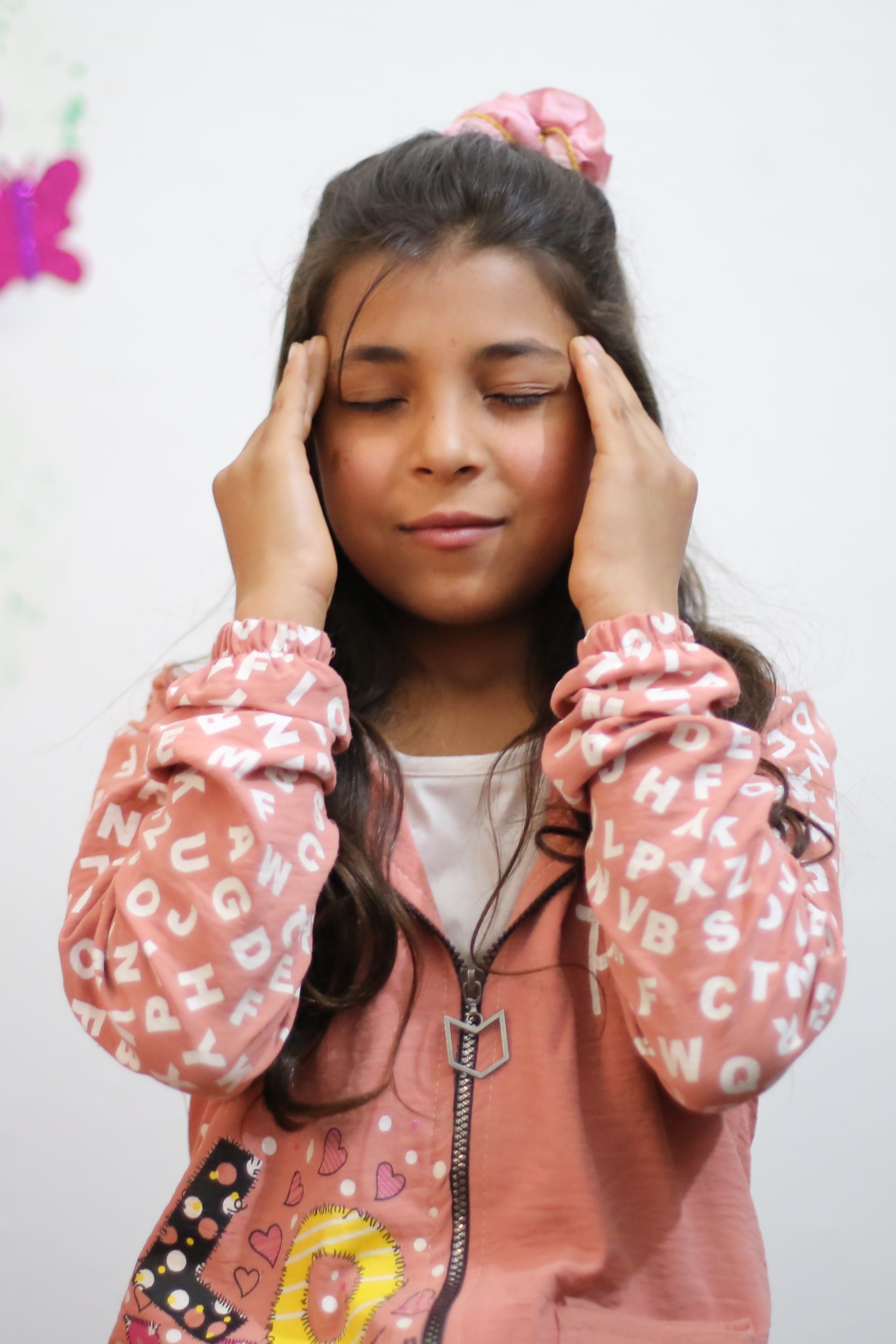 young syrian girl with her eyes closed and her fingers at her temples