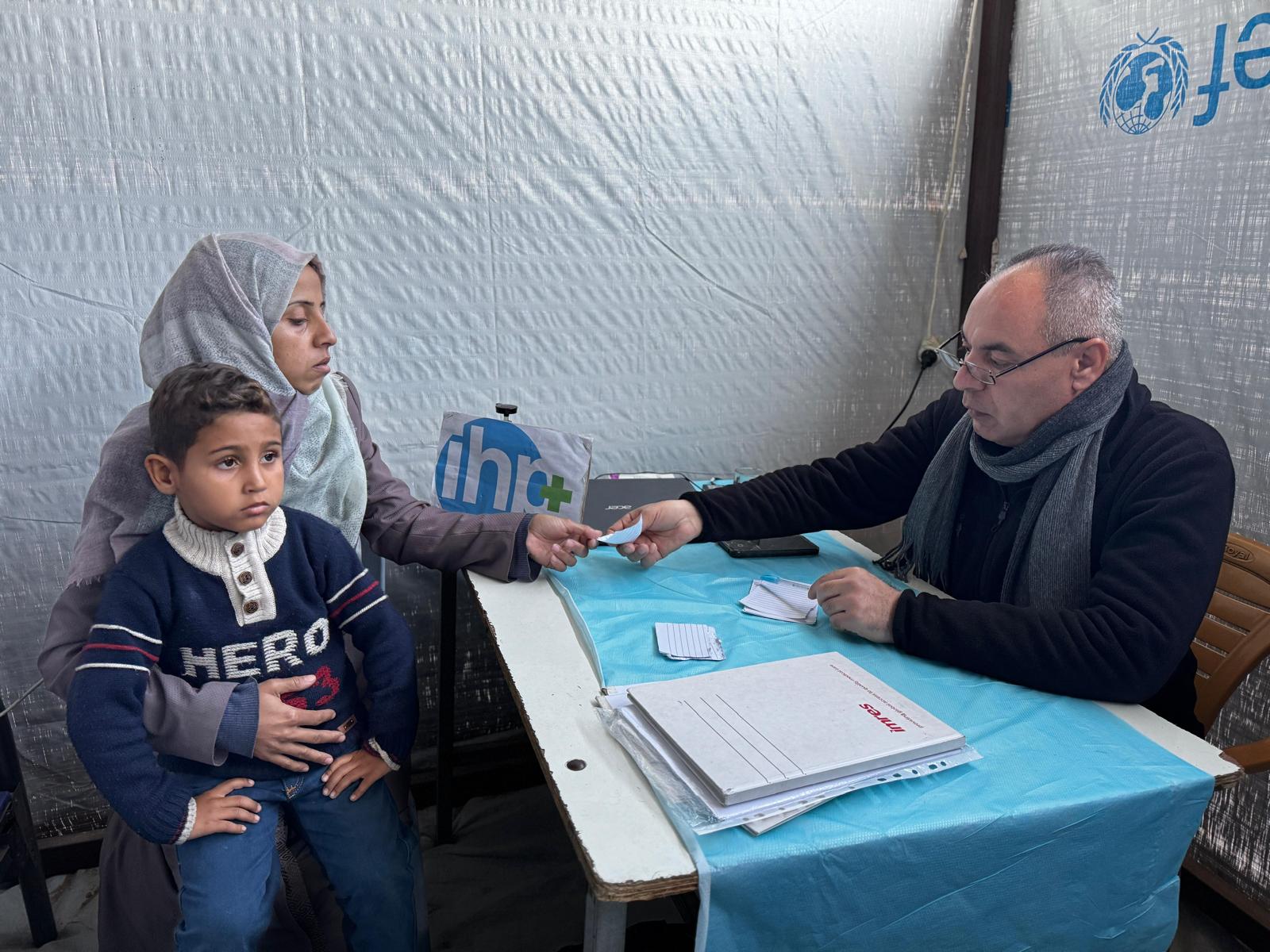 A mother and son in Gaza receiving medicine from a doctor at a field clinic