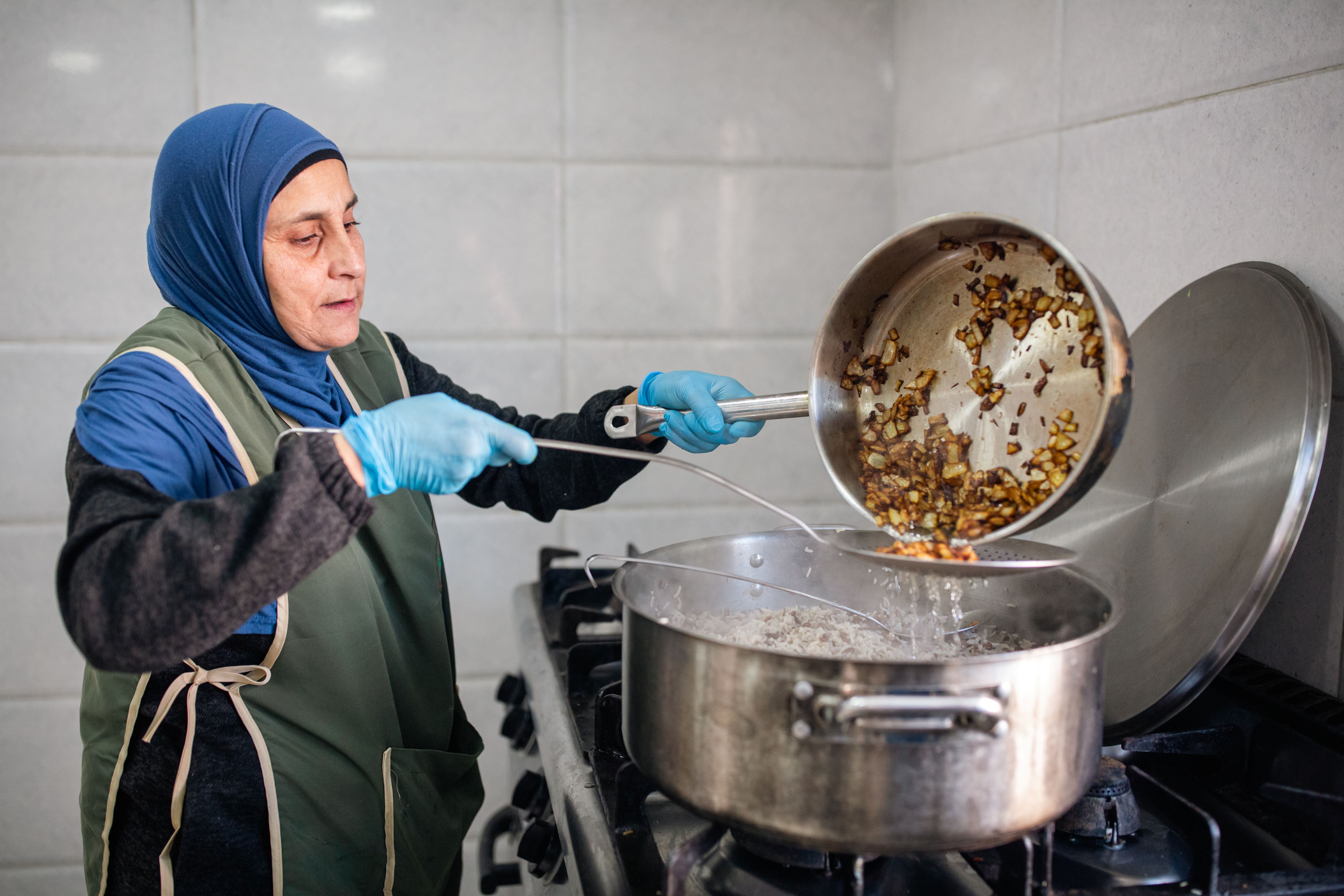 Gaza woman pouring food from a pan into a pot